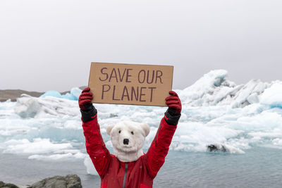 Activist on polar bear mask with a message for humanity save our planet in icelandic glaciers