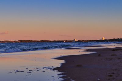 Scenic view of beach against clear sky during sunset