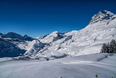 Scenic view of snowcapped mountains against clear blue sky