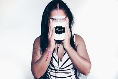 Woman holding milk jar in front of face against white background