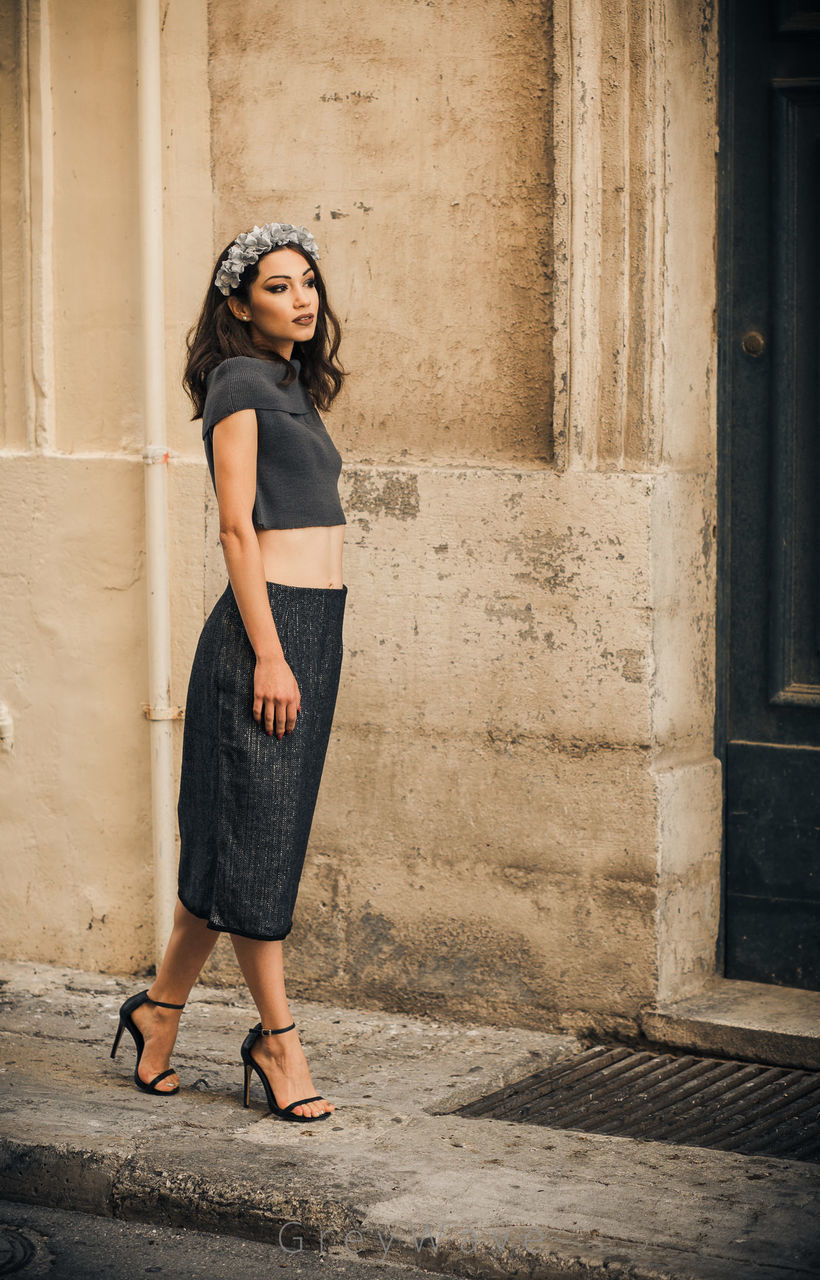 FULL LENGTH OF WOMAN STANDING AGAINST WALL