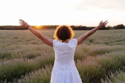 Rear view of woman standing on field against sky