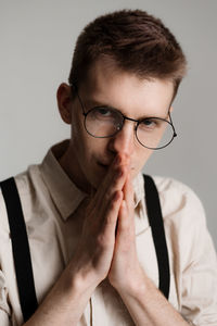 Close-up portrait of young man wearing eyeglasses against white background