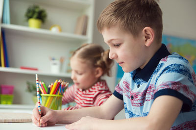 Boy looking away while sitting on table