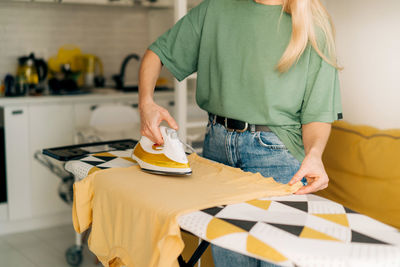 Woman housewife does housework and irons clothes at home.