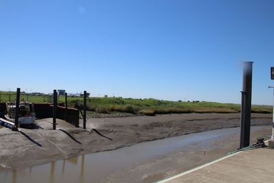 Wooden posts on field against clear blue sky