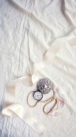 Directly above view of pocket watch on white bed