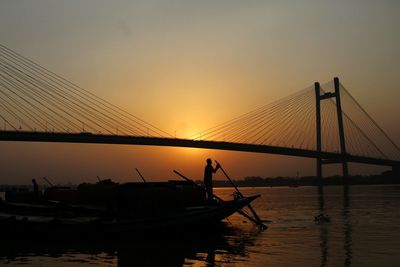 Silhouette of suspension bridge against sky during sunset