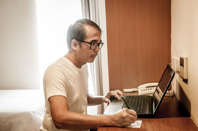 Side view of man using laptop at home