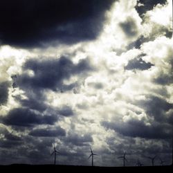 Low angle view of electricity pylon against cloudy sky