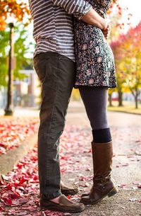 Low section of couple embracing on footpath during autumn