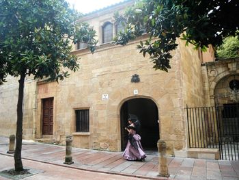 Woman standing by tree against building