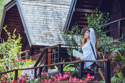 Woman standing by flowers outside house