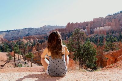 Rear view of woman standing amidst plants against sky