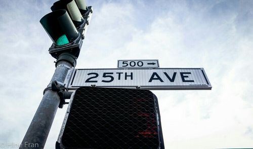 Low angle view of road sign against cloudy sky