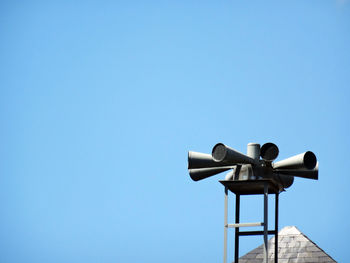 Low angle view of telephone pole against clear blue sky