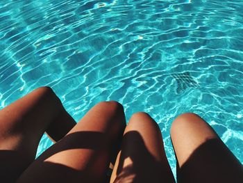 Low section of women relaxing in swimming pool