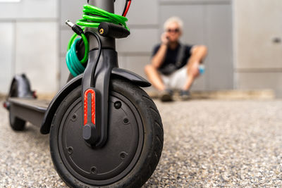 Commuter hipster man with electric scooter using smartphone in the suburbs. eco transport concept 