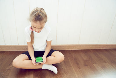 Portrait of young woman sitting on hardwood floor at home