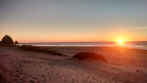 Scenic view of beach against clear sky during sunset