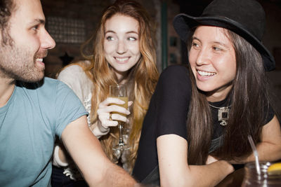 Three friends chat over drinks at an outdoor tiki bar