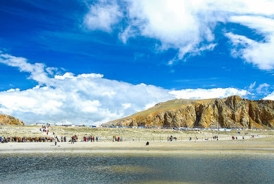 Panoramic view of people on landscape against blue sky