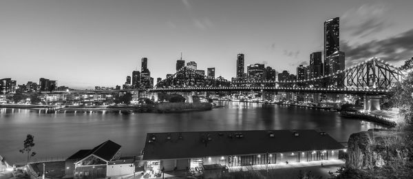 Bridge over river by buildings against sky in city