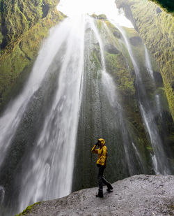 Man standing by waterfall