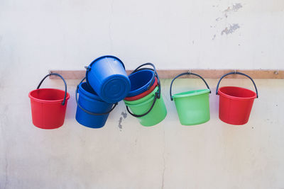 Multi colored buckets hanging on hooks outdoors