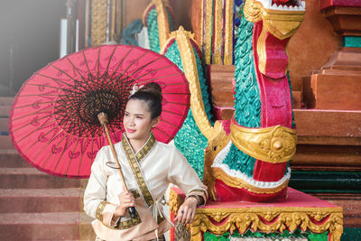 Full length of woman holding multi colored umbrella