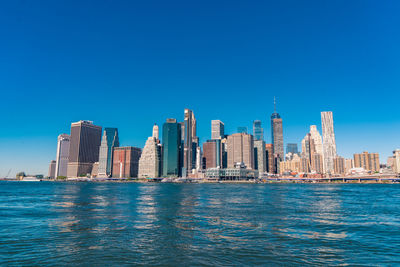 Buildings in city against clear blue sky