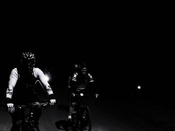 People riding bicycle on road at night