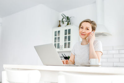 Young woman using mobile phone while sitting on table