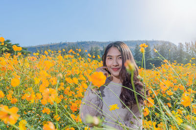 Portrait of woman standing by yellow flowering plants