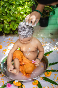 Cute toddler baby boy bathing with shampoo in decorated bathtub at outdoor from unique perspective