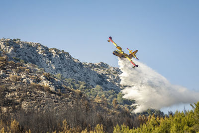 Firefighting airplane pouring water on forest