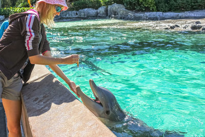 Woman touching fish in water