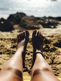 Low section of woman legs on sand at beach