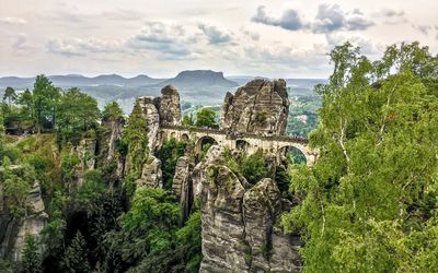 Scenic view of mountains against cloudy sky with ancient bridge 