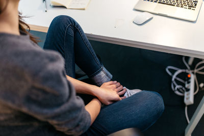 Low section of woman sitting by table