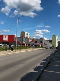 Road by buildings in city against sky