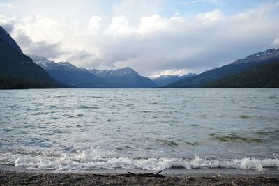 Scenic view of sea and mountains against cloudy sky