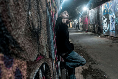 Side view of young man standing on street in city