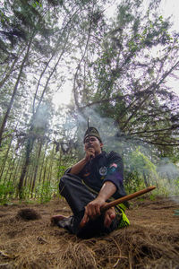 Portrait of young man sitting in forest