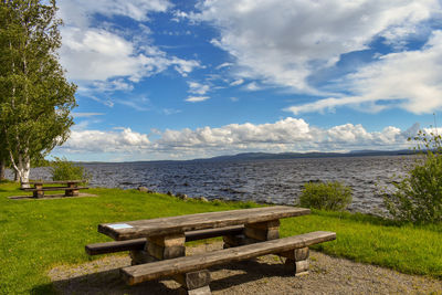 Bench by sea against sky