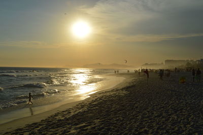 Silhouette people on beach against sky during sunset