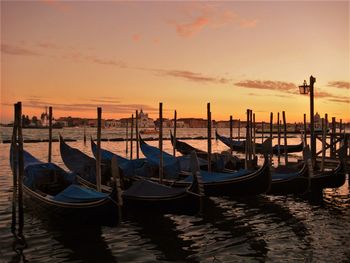 Boats moored in canal at sunset