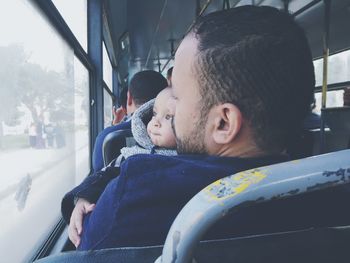 Close-up of man with son traveling in bus