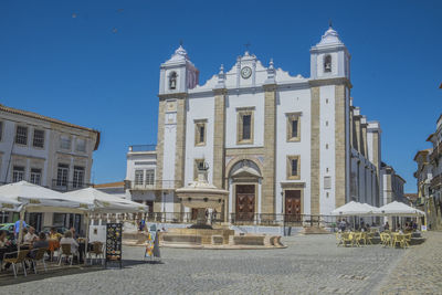 Group of people in front of building against blue sky