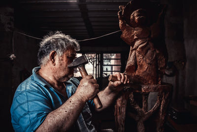 Close-up of man carving wood in workshop